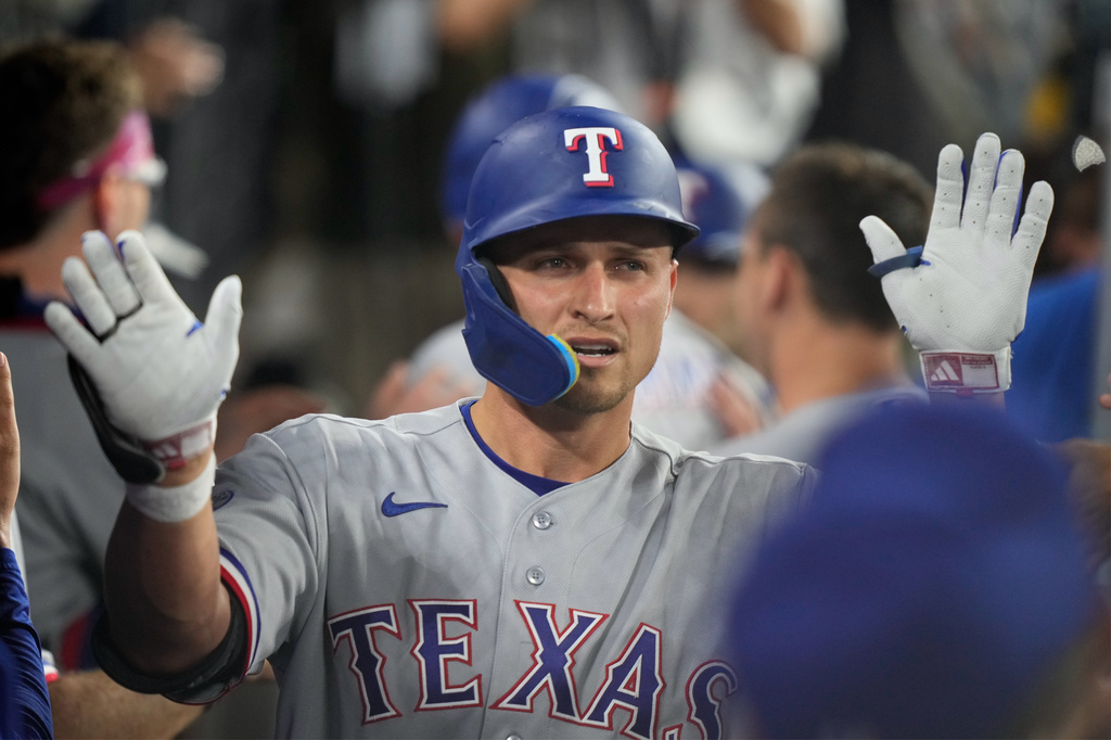 Texas Rangers' Corey Seager is congratulated by teammates in the dugout after hitting a three-run home run during the third inning of a baseball game against the Los Angeles Dodgers, Friday, April 10, 2026, in Los Angeles. (AP Photo/Mark J. Terrill)
