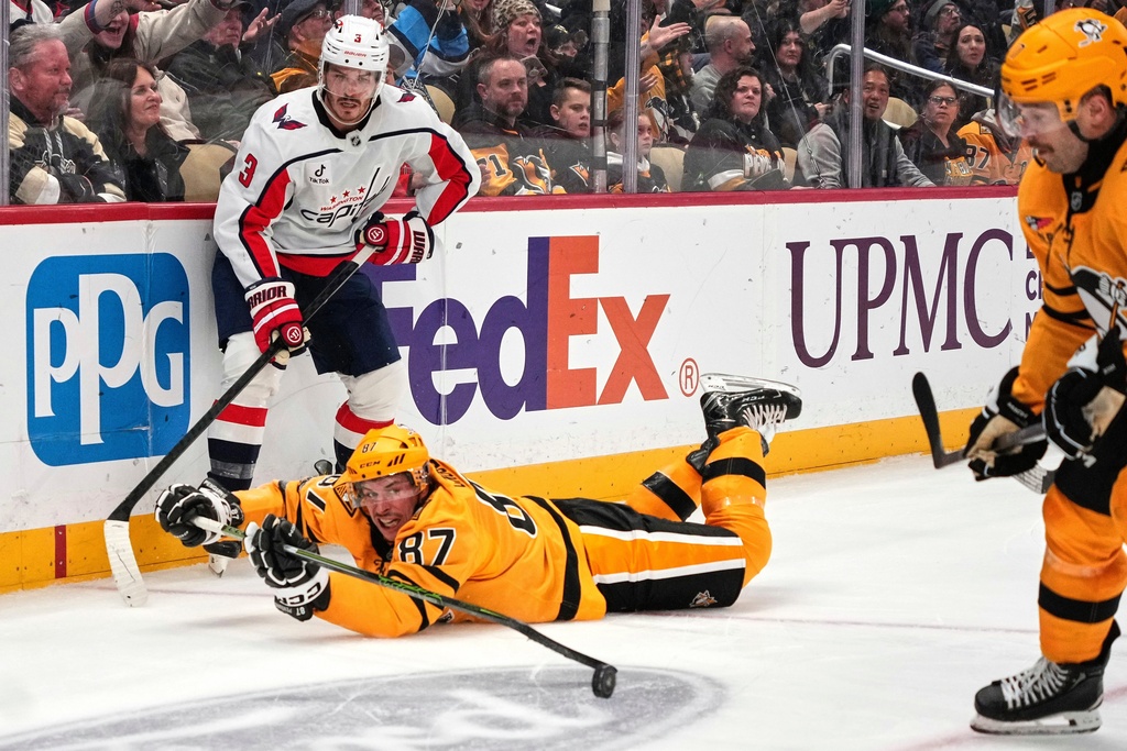 Pittsburgh Penguins' Sidney Crosby (87) gets of a pass to Bryan Rust, right, with Washington Capitals' Matt Roy (3) defending during the second period of an NHL hockey game in Pittsburgh, Thursday, Nov. 6, 2025. (AP Photo/Gene J. Puskar)