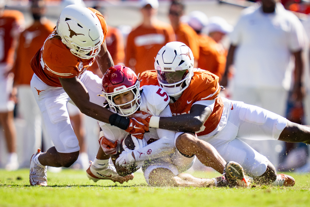 The Texas defense bring down Oklahoma wide receiver Isaiah Sategna III (5) in the first quarter of an NCAA college football game at the Cotton Bowl in Dallas, Saturday, Oct. 11, 2025. (Sara Diggins/Austin American-Statesman via AP)