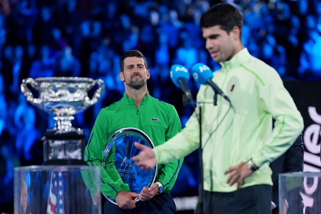 Novak Djokovic of Serbia watches Carlos Alcaraz of Spain give his victory speech after winning the men's singles final at the Australian Open tennis championship in Melbourne, Australia, Sunday, Feb. 1, 2026. (AP Photo/Aaron Favila)