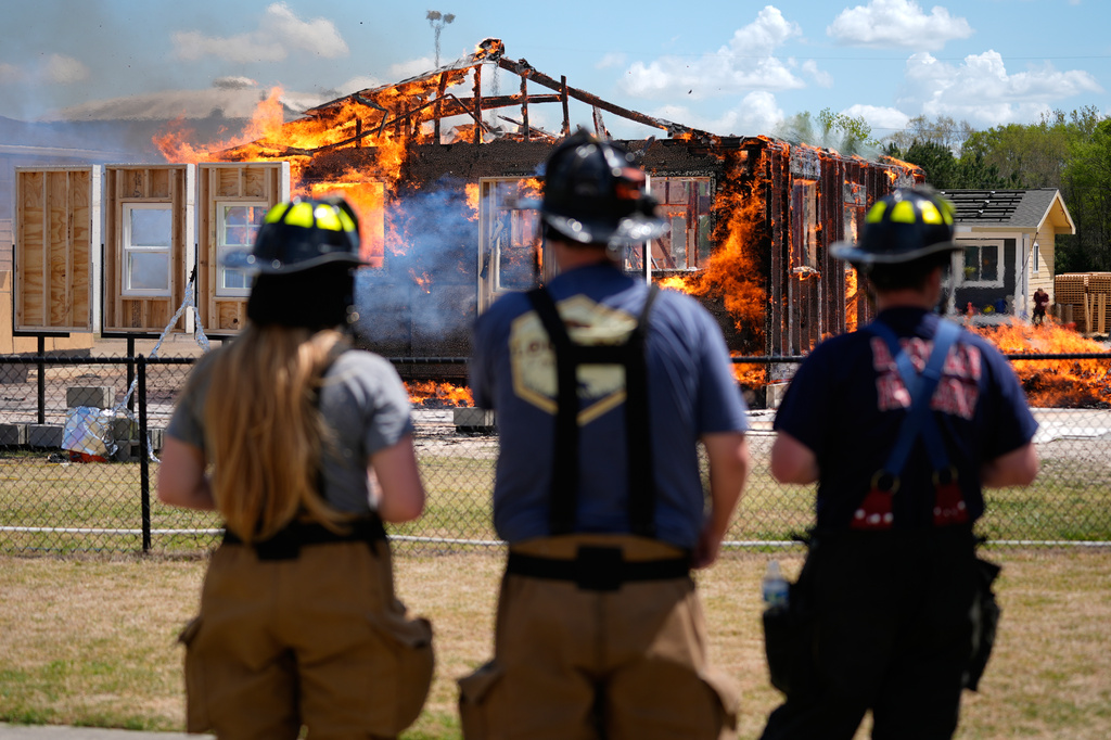 Chester County Firefighters Elizabeth Stevenson, from left, Michael Mackey and Charles Lee, watch an accessory dwelling unit burn during an experiment at the Institute for Business & Home Safety center Wednesday, April 1, 2026, in Richburg, S.C. (AP Photo/Erik Verduzco)