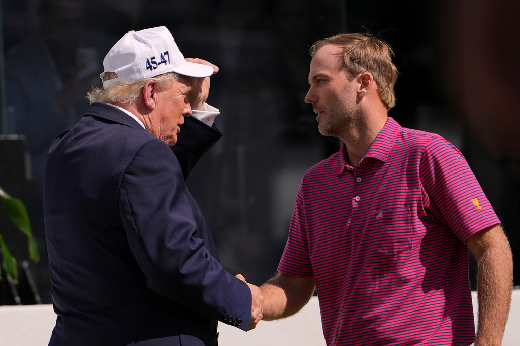President Donald Trump, left, greets USA teams' Russell Henley at the Presidents Cup golf tournament at Medinah Country Club, Sunday, Sept. 27, 2026, in Medinah, Ill. (AP Photo/Julia Demaree Nikhinson)