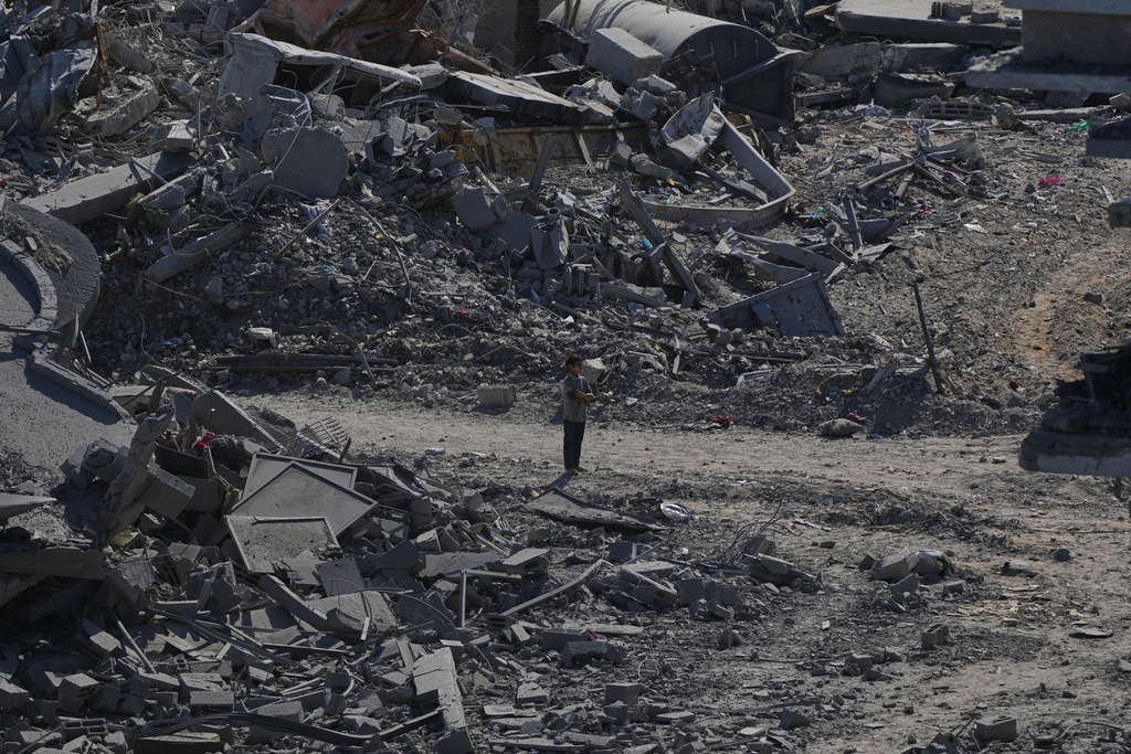 A Palestinian boy stands amid destroyed buildings in Gaza City, Saturday, Oct. 11, 2025, after Israel and Hamas agreed to a pause in their war and the release of the remaining hostages. (AP Photo/Abdel Kareem Hana)