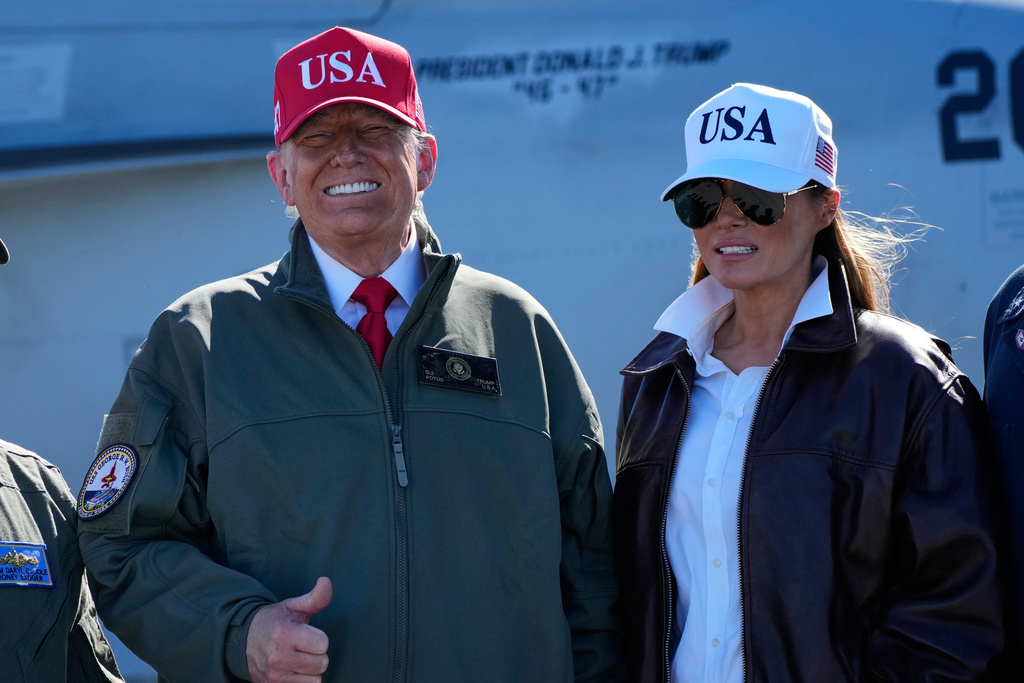 President Donald Trump and first lady Melania Trump pose in front of a F/A-18E fighter jet with President Donald Trump's name on it, as part of the Navy's 250th anniversary celebration, aboard the USS George H.W. Bush aircraft carrier in the Atlantic Ocean off the coast of Norfolk, Va., Sunday, Oct. 5, 2025. (AP Photo/Alex Brandon)
