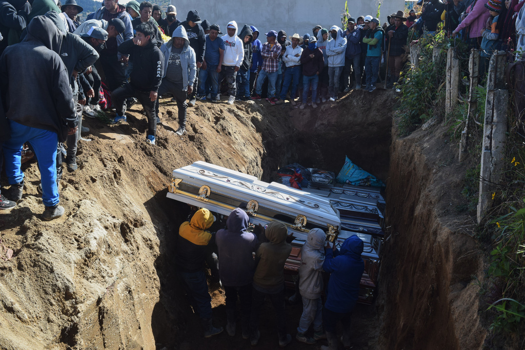 People bury victims in a mass grave following an attack by armed men on a military post and a police station in Nahuala, Guatemala, Sunday, Dec. 14, 2025. (AP Photo/Mariano Rosales)