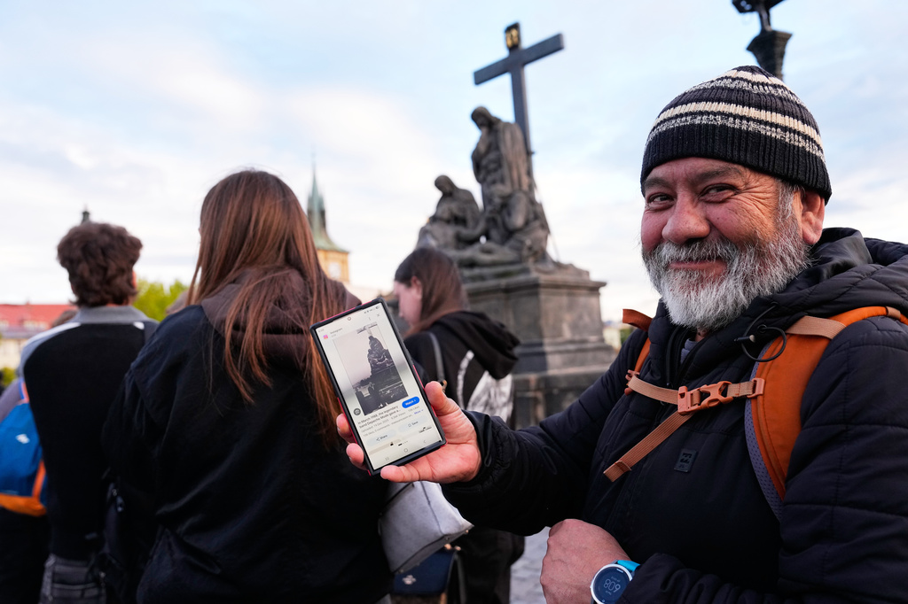Jorge Sanchez from Los Angeles displays a famous photo of two members of Depeche Mode, taken by Dutch photographer Anton Corbijn in 1988, as he waits in line to recreate this image by the Pieta statue at the Charles Bridge in Prague, Czech Republic, Thursday, Sept. 24, 2026. (AP Photo/Petr David Josek)