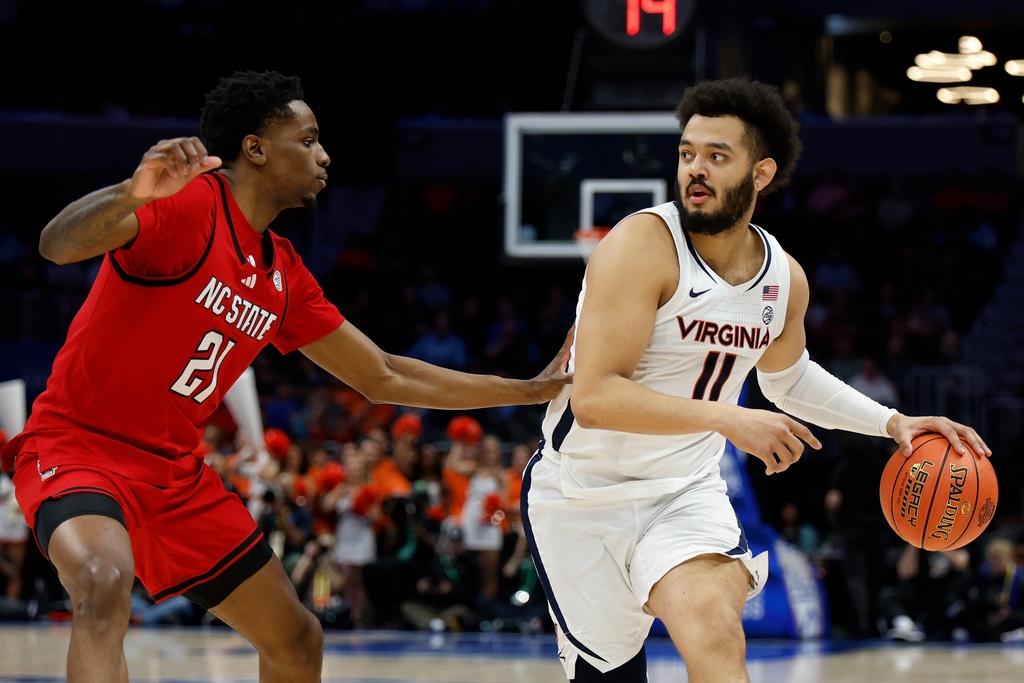 Virginia forward Devin Tillis (11) looks to pass as North Carolina State guard Terrance Arceneaux defends during the first half of an NCAA college basketball game in the quarterfinals of the Atlantic Coast Conference tournament in Charlotte, N.C., Thursday, March 12, 2026. (AP Photo/Nell Redmond)
