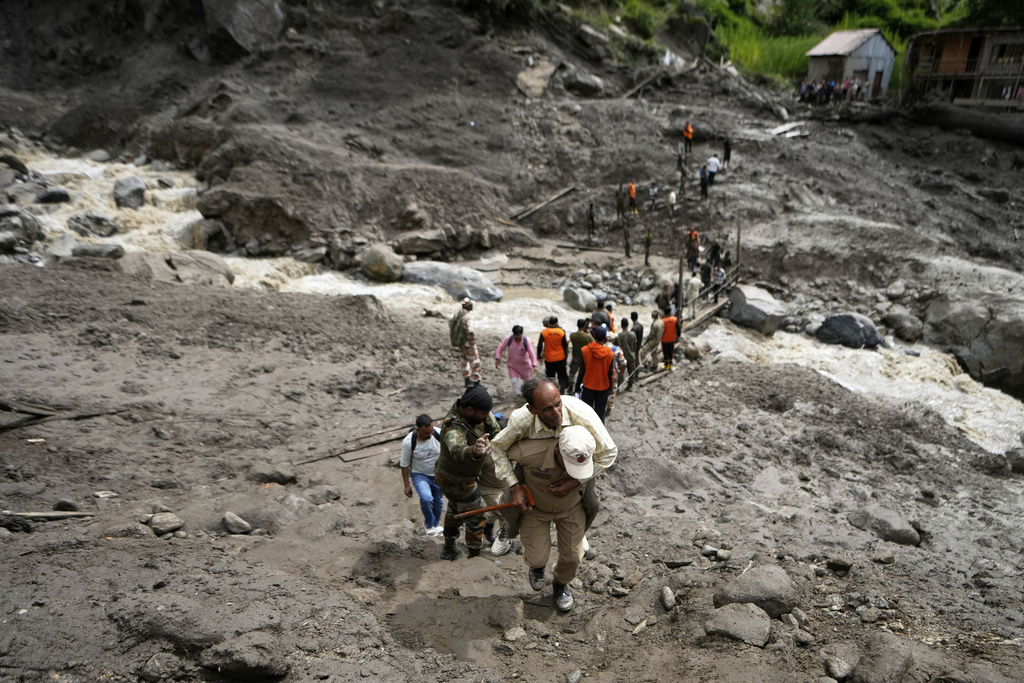 Stranded pilgrims cross a water channel using a makeshift bridge, the day after flash floods in Chositi village, Kishtwar district, Indian-controlled Kashmir, Friday, Aug. 15, 2025. (AP Photo/Channi Anand)