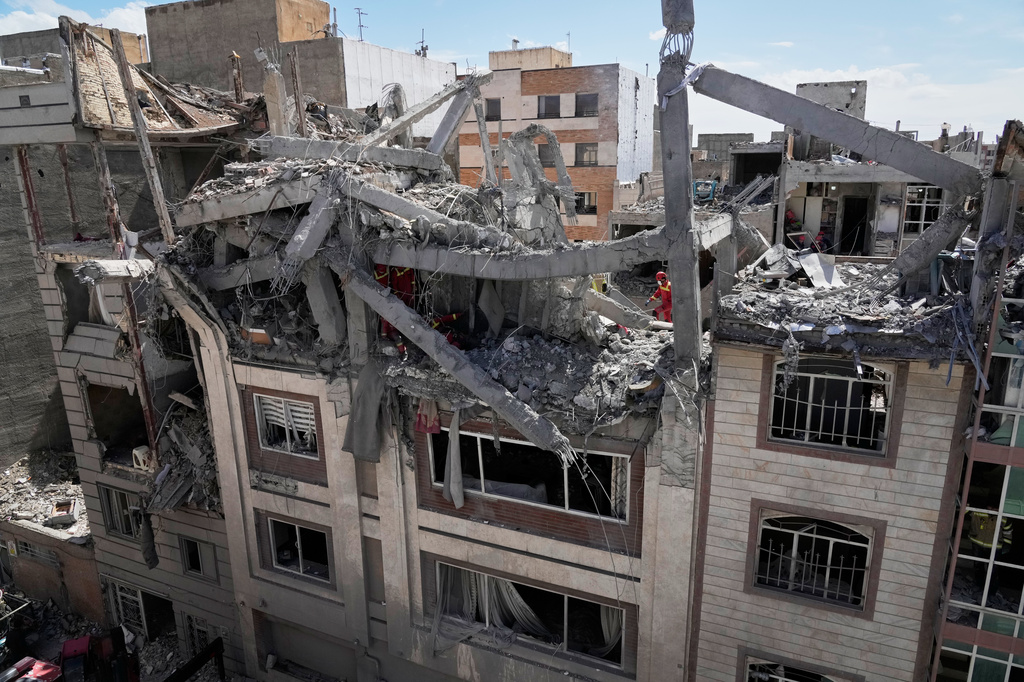 First responders inspect a residential building hit in an earlier U.S.-Israeli strike in Tehran, Friday, March 27, 2026. (AP Photo/Vahid Salemi)