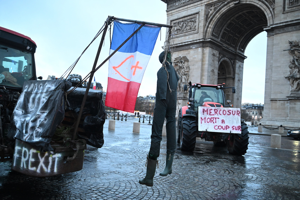 A mannequin hangs from a tractor as farmers protest at the Arc de Triomphe against the Mercosur trade alliance with South America countries but also against EU farming policy or mass cull of cows ordered to contain the spread of a skin disease, Thursday, Jan. 8, 2026 in Paris. Poster at right reads: Mercosur, death for sure. (AP Photo/Emma Da Silva)