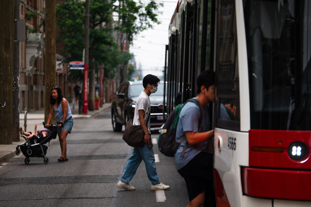 A person in a face mask boards a streetcar in Toronto as wildfire smoke fills the city, on Wednesday, July 15, 2026. (Laura Proctor/The Canadian Press via AP)