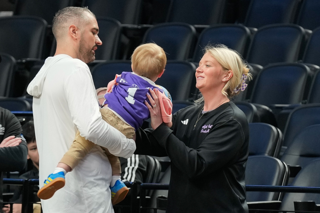 High Point head coach Flynn Clayman, left, hands his son, Quinn, to his wife Katie Clayman, assistant coach for the High Point women's basketball team, right, during practice prior to the first round of the NCAA college basketball tournament on Wednesday, March 18, 2026, in Portland, Ore. (AP Photo/Jenny Kane)