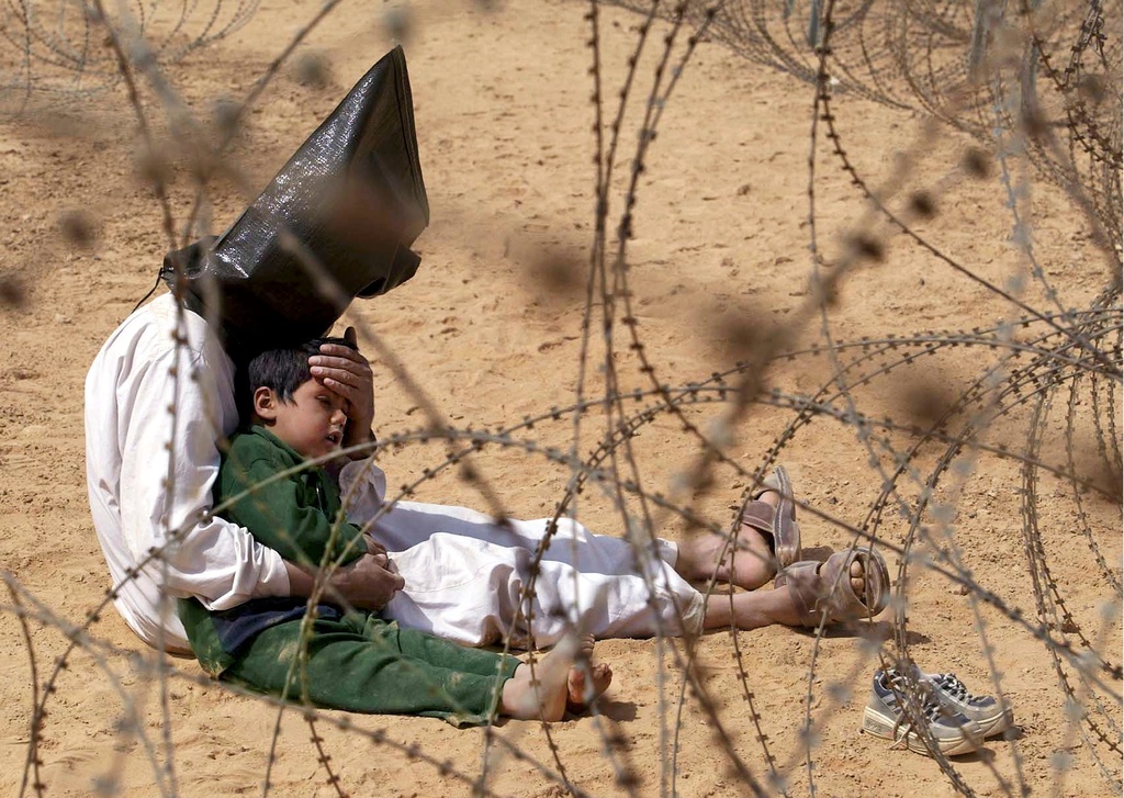 FILE - An Iraqi prisoner of war comforts his 4-year-old son at a regroupment center for POWs of the 101st Airborne Division near An Najaf, March 31, 2003. (AP Photo/Jean-Marc Bouju, File)