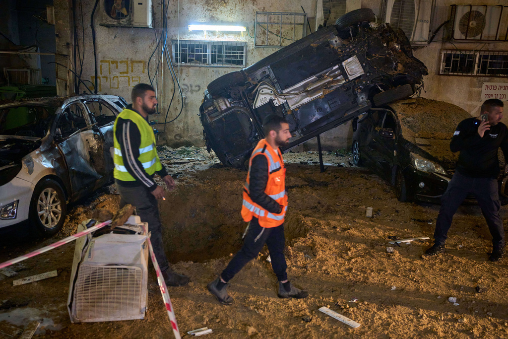Israeli security forces inspect damage at the site of an Iranian missile strike in Holon, central Israel, Sunday, March 15, 2026. (AP Photo/Ohad Zwigenberg)