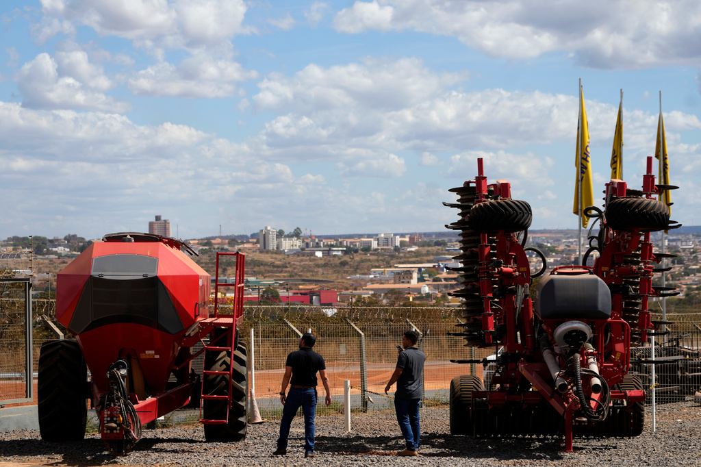 Salesmen walk among agricultural machinery displayed at an equipment dealership, representing one of the sectors affected by U.S. tariffs, on the outskirts of Brasilia, Brazil, Wednesday, July 22, 2026. (AP Photo/Eraldo Peres)