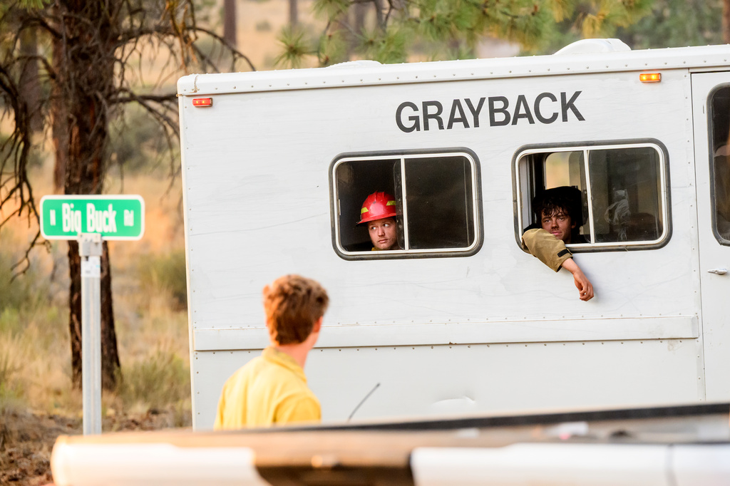 Firefighters ride in a buggy while battling the Akawa Butte fire on Friday, July 24, 2026, near Sisters, Ore. (AP Photo/Noah Berger)