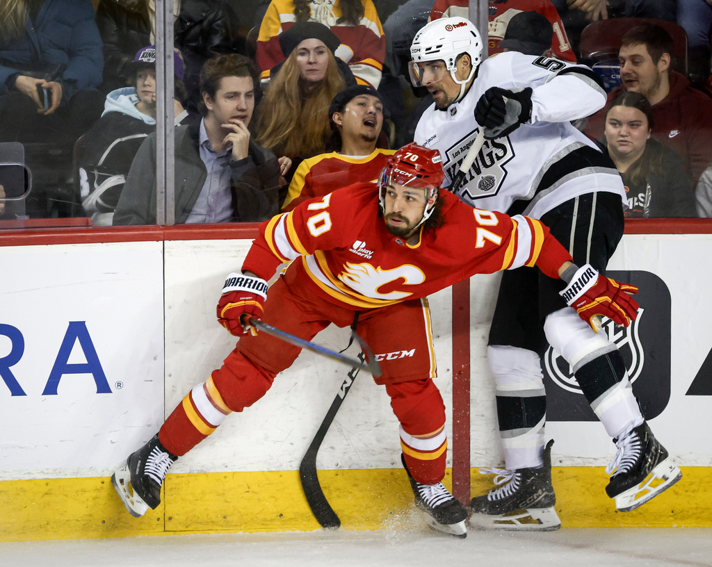 Los Angeles Kings' Cody Ceci, right, is checked by Calgary Flames' Ryan Lomberg during the second period of an NHL hockey game in Calgary on Tuesday, March 24, 2026. (Jeff McIntosh/The Canadian Press via AP)