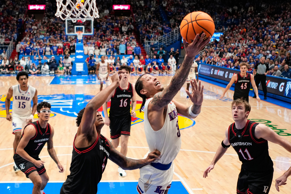 Kansas guard Tre White (3) gets past Davidson guard Josh Scovens (4) to put up a shot during the first half of an NCAA college basketball game Monday, Dec. 22, 2025, in Lawrence, Kan. (AP Photo/Charlie Riedel)