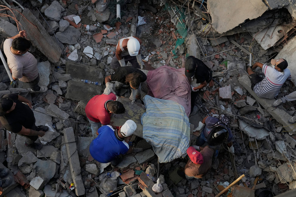 Residents pull a body from the rubble two days after earthquakes struck La Guaira, Venezuela, Friday, June 26, 2026. (AP Photo/Ariana Cubillos)