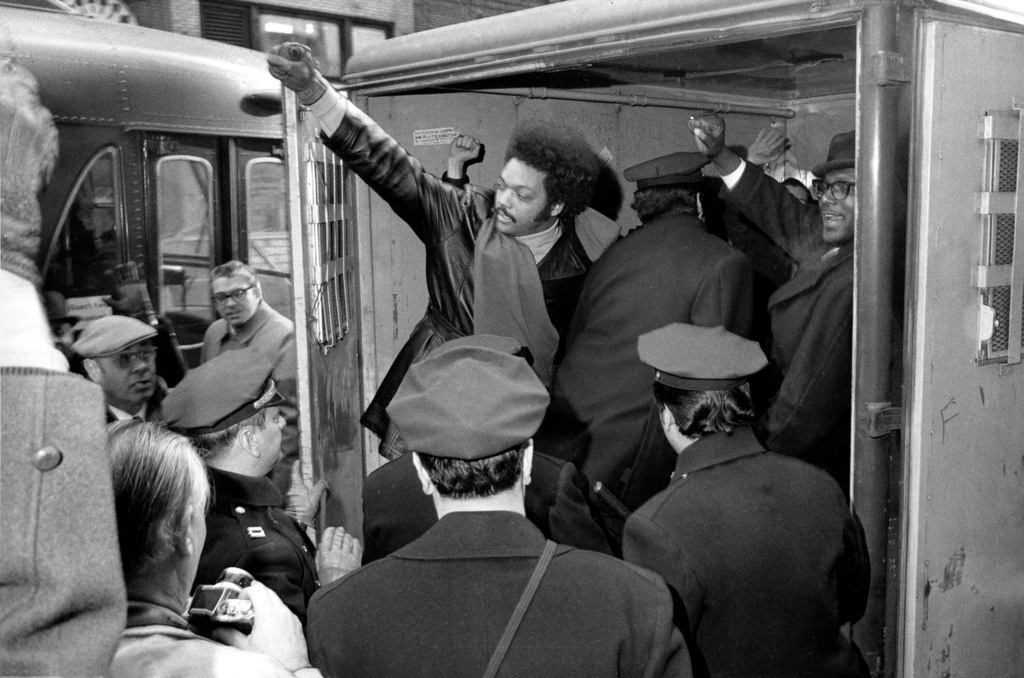 FILE - Rev. Jesse Jackson raises a clenched fist from a police van after he and 11 others from Operation Breadbasket were arrested during a sit-in at the Atlantic and Pacific Tea Co., offices in New York, Feb. 2, 1971. (AP Photo/Marty Lederhandler, file)