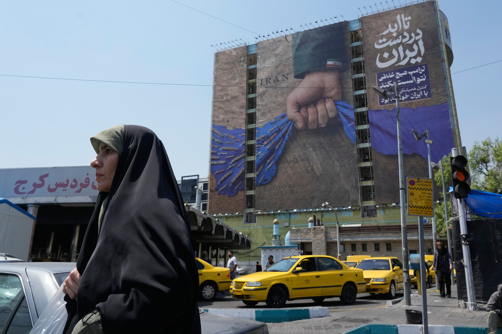 A woman walks past a billboard that shows a graphic depicting a military personnel's hand holding the Strait of Hormuz in his fist with signs which read in Farsi: "In Iran's hands forever," "Trump couldn't do a damn thing," " The control of Strait of Hormuz will be Iran's forever," in Vanak Square, in northern Tehran, Iran, Thursday, April 16, 2026. (AP Photo/Vahid Salemi)