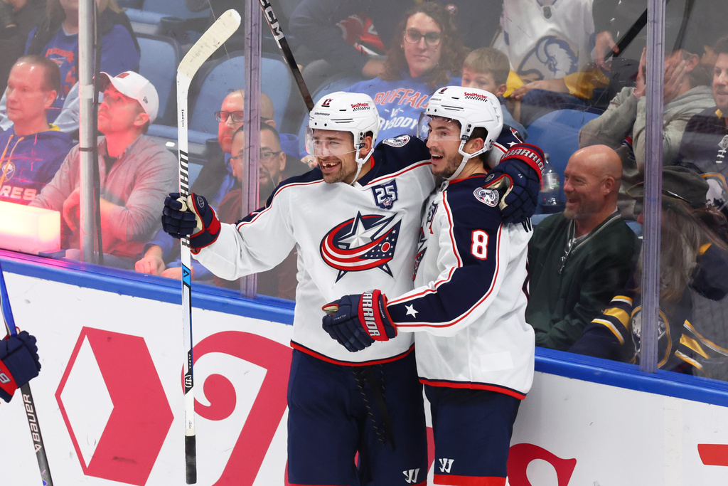 Columbus Blue Jackets left wing Miles Wood (11) celebrates his game winning goal with defenseman Zach Werenski (8) during the overtime period of an NHL hockey game against the Buffalo Sabres Tuesday, Oct. 28, 2025, in Buffalo, N.Y. (AP Photo/Jeffrey T. Barnes)
