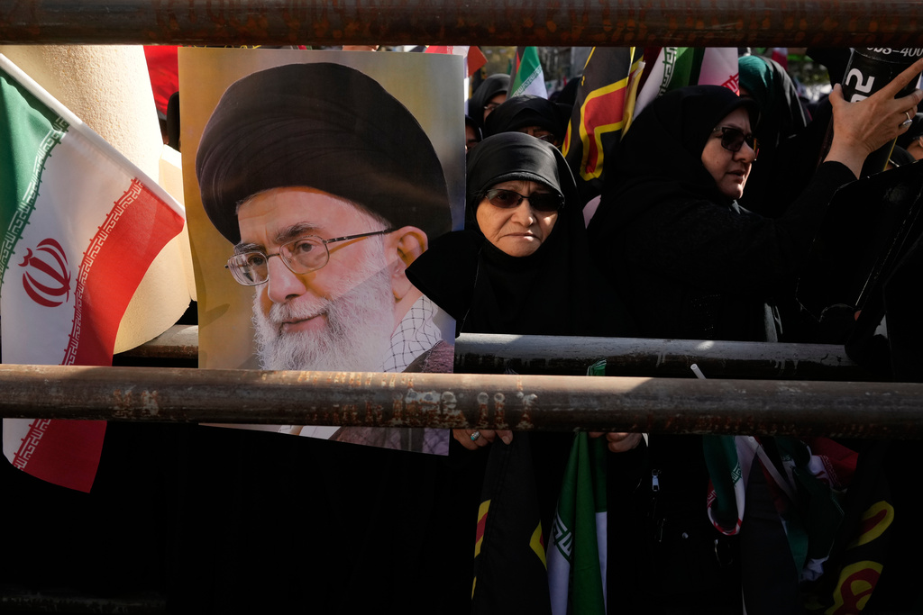 Demonstrators hold a poster of the Iranian Supreme Leader Ayatollah Ali Khamenei and an Iranian flag during an annual rally in front of the former U.S. Embassy in Tehran, celebrating the anniversary of the 1979 takeover of the embassy, Iran, Tuesday, Nov. 4, 2025. (AP Photo/Vahid Salemi)