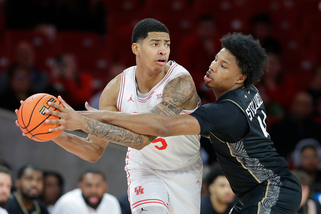 Houston center Chris Cenac Jr., left, looks to pass the ball as Central Florida forward Jamichael Stillwell, right, reaches in during the first half of an NCAA college basketball game, Wednesday, Jan., 4, 2026, in Houston. (AP Photo/Michael Wyke)