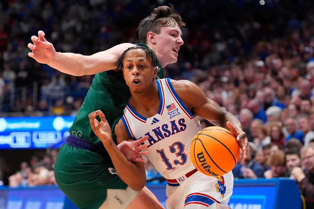 Kansas guard Elmarko Jackson (13) drives past Green Bay forward Marcus Hall during the first half of an NCAA college basketball game Monday, Nov. 3, 2025, in Lawrence, Kan. (AP Photo/Charlie Riedel)