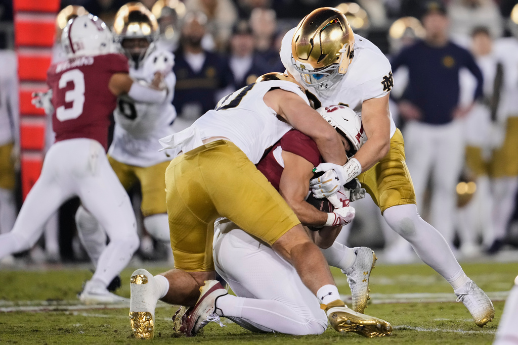 Stanford wide receiver Bryce Farrell, center, is tackled by Notre Dame defensive lineman Joshua Burnham (40) and linebacker Drayk Bowen (34) during the first half of an NCAA college football game, Saturday, Nov. 29, 2025, in Stanford, Calif. (AP Photo/Godofredo A. Vásquez)