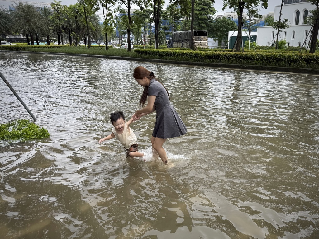 A mother and her son play in the flood in the aftermath of Typhoon Kajiki in Hanoi, Vietnam, Wednesday, Aug. 27, 2025. (AP Photo/Hau Dinh)