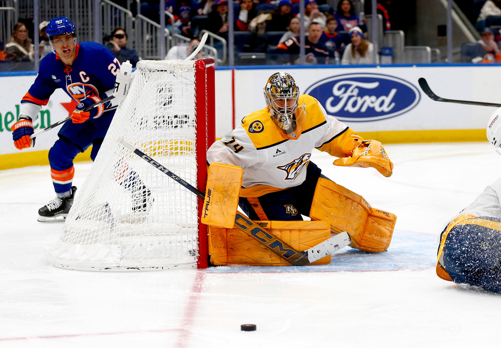 Nashville Predators goalie Juuse Saros, right, keeps his eye on the puck as New York Islanders forward Anders Lee skates behind the net during the second period of an NHL hockey game Saturday, Jan. 31, 2026, in Elmont, N.Y. (AP Photo/John Munson)