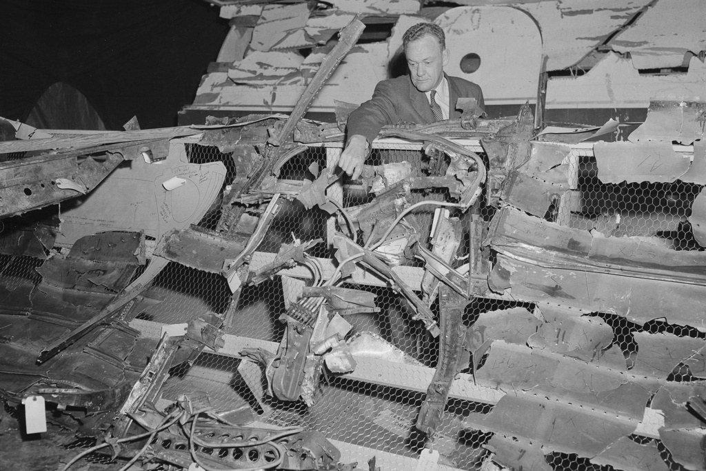 FILE - United Airlines official W.C. Mentzer points in Denver toward the reconstructed baggage compartment on Nov. 17, 1955, where officials believe the blast which caused the United Airlines plane to crash on Nov. 1, 1955. (AP Photo/Edward O. Eisenhand, File)