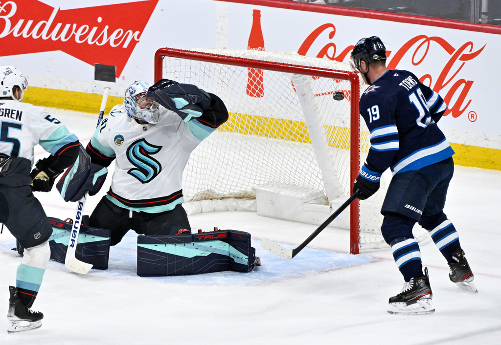 A shot by Winnipeg Jets' Kyle Connor (not shown) gets past Seattle Kraken goaltender Philipp Grubauer, second from right, for a goal as Jets' Jonathan Toews (19) looks for a rebound during second-period NHL hockey game action in Winnipeg, Manitoba, Monday, April 6, 2026. (Fred Greenslade/The Canadian Press via AP)