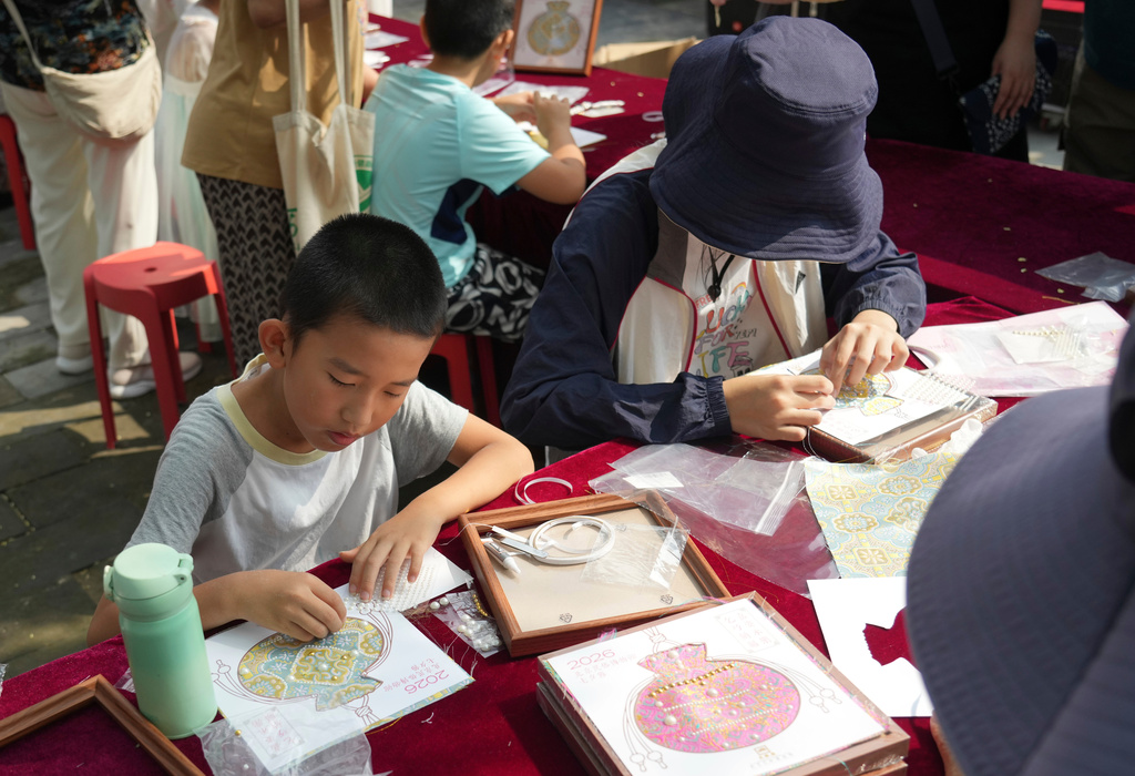 A child makes a sachet-shaped Song brocade pearl painting during a festival to celebrate Qixi at the Beijing Folk Custom Museum in Beijing, Wednesday, Aug. 19, 2026. (AP Photo/Achmad Ibrahim)