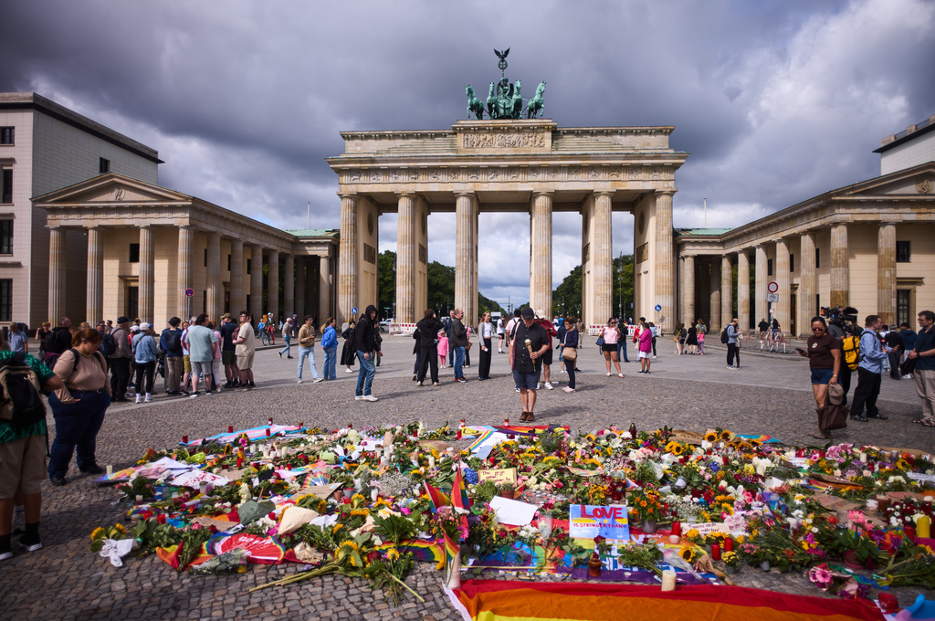 Flowers and rainbow flags placed in front of the Brandenburg Gate commemorating the victims of a car attack on Saturday's Pride March in Berlin, Germany, Monday, July 27, 2026. (AP Photo/Markus Schreiber)