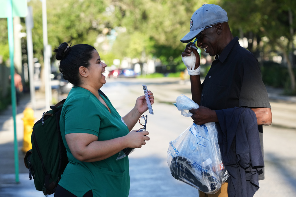 Nadien D'arcangelo, of the Frame Project, left, tests eyeglasses with Terry Rhodin, right, while working with the Miami Street Medicine team to provide medical services to homeless people, Saturday, Sept. 20, 2025, in Miami. (AP Photo/Lynne Sladky)