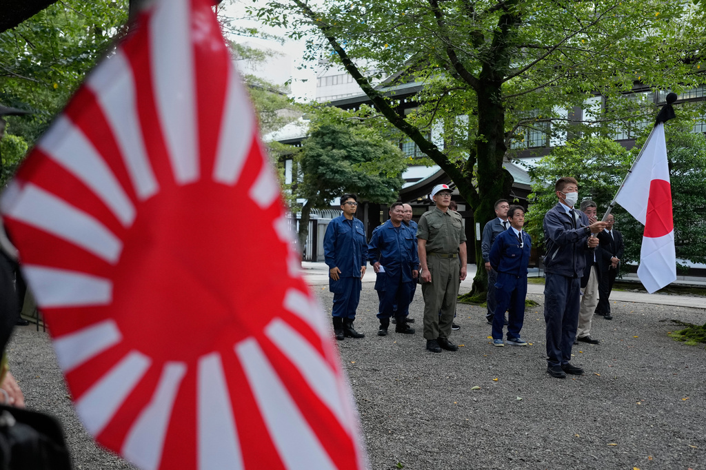 Visitors carry Japanese flags and a rising sun flag at Yasukuni Shrine, which honors Japan's war dead, including convicted war criminals, as the country marks the 81st anniversary of the end of World War II Saturday, Aug. 15, 2026, in Tokyo. (AP Photo/Eugene Hoshiko)