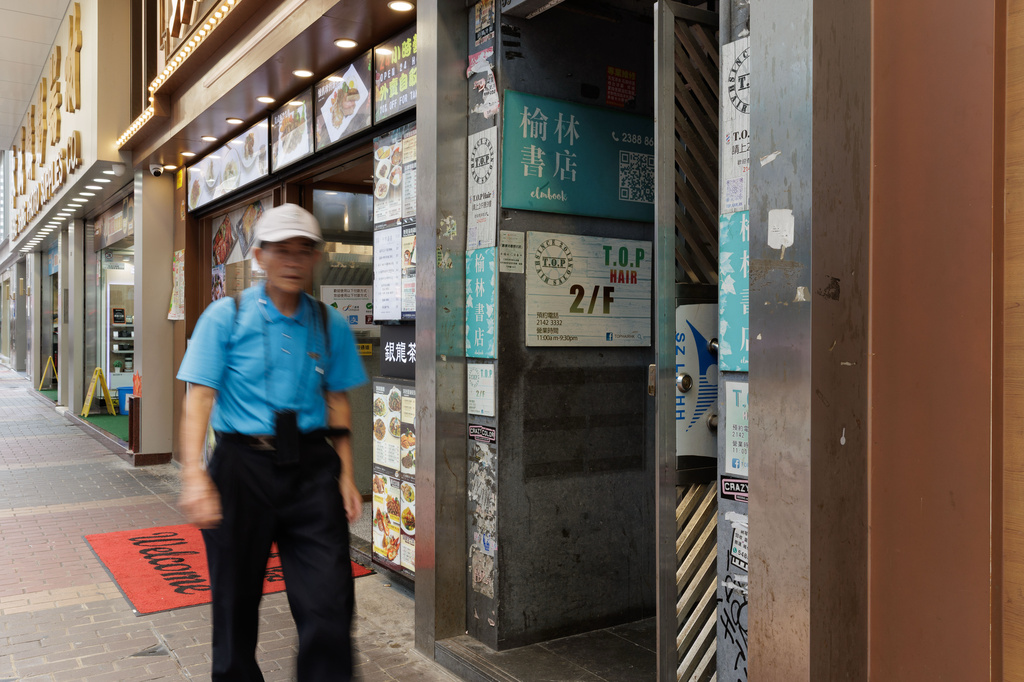 A pedestrian passes a narrow street entrance leading to Elmbook - an independent bookstore that opened in 1997, in Hong Kong, Friday, Aug. 14, 2026. (AP Photo/May James)
