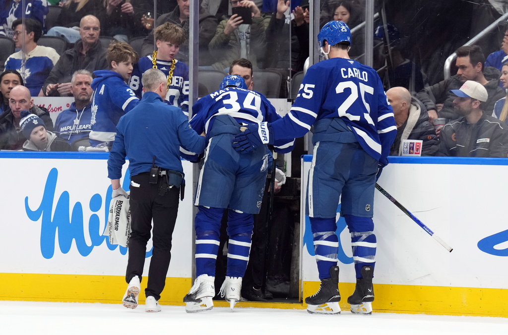 Toronto Maple Leafs Auston Matthews (34) is helped off the ice after being injured by Anaheim Ducks Radko Gudas during the second period of an NHL hockey game in Toronto, Thursday, March 12, 2026. (Nathan Denette/The Canadian Press via AP)