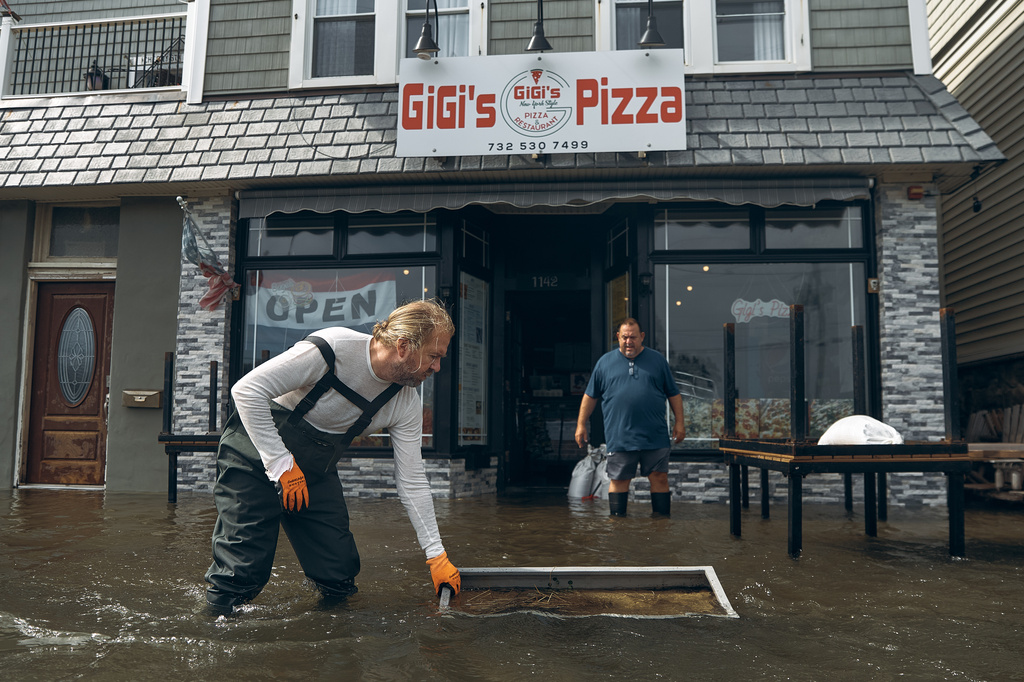 People clean a flooded pizza restaurant during a nor'easter storm on Sunday, Sept. 27, 2026, in Sea Bright, N.J. (AP Photo/Andres Kudacki)