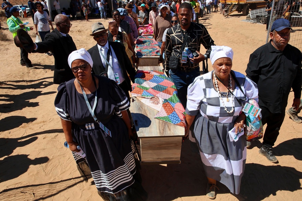 In this photo provided by the South African Government Communications and Information Services, families and community members carry coffins during a reburial of remains of dozens of Africans whose bodies were dug up and sent to Europe for scientific research long ago, in Steinkopf, South Africa, Monday, March 23, 2026. (Jairus Mmutle/GCIS via AP)
