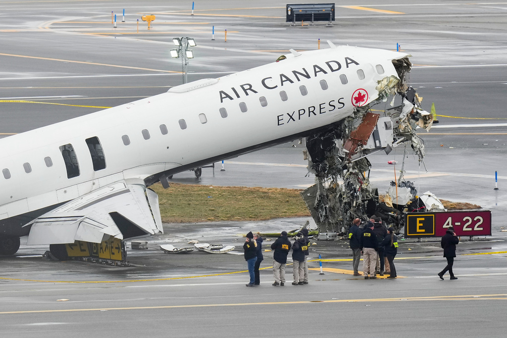 Officials with the National Transportation Safety Board investigate the site, Monday, March 23, 2026, where an Air Canada jet came to rest after colliding with a Port Authority firetruck at LaGuardia Airport, shortly after landing Sunday night in New York. (AP Photo/Seth Wenig)