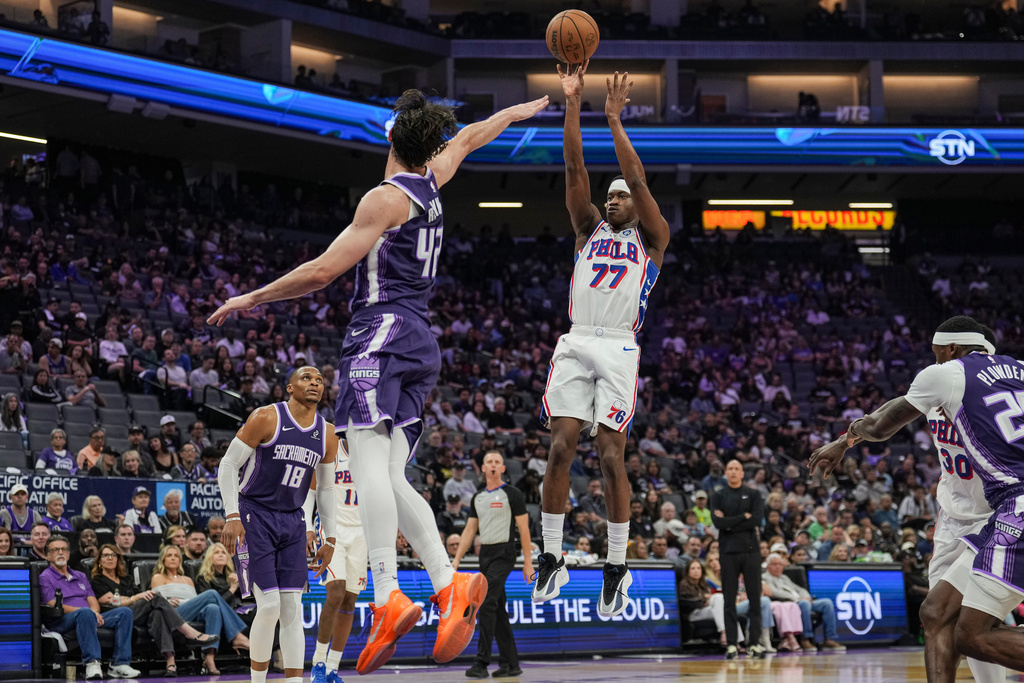 Philadelphia 76ers guard Vj Edgecombe (77) shoots a three-point basket over Sacramento Kings center Maxime Raynaud (42) during the first half of an NBA basketball game, Thursday, March 19, 2026, in Sacramento, Calif. (AP Photo/Justine Willard)
