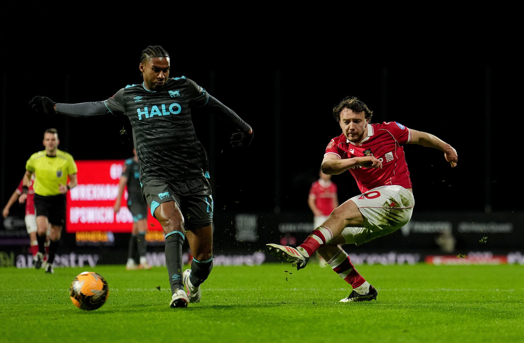Wrexham's Ollie Rathbone, right, has a shot at goal against Ipswich Town during an English FA Cup fourth round soccer, Friday, Feb. 13, 2026, in Wrexham, Wales. (Martin Rickett/PA via AP)