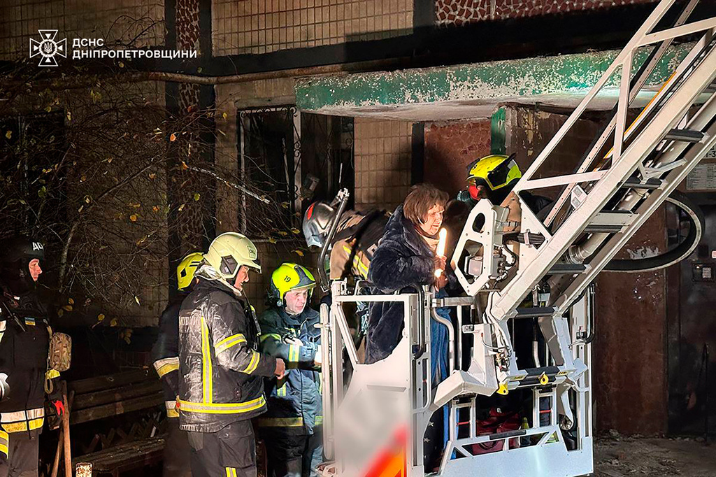 In this photo provided by the Ukrainian Emergency Service, firefighters evacuate a resident following a Russian rocket attack that hit a multi-storey apartment building in Dnipro, Ukraine, Saturday, Nov. 8, 2025. (Ukrainian Emergency Service via AP)