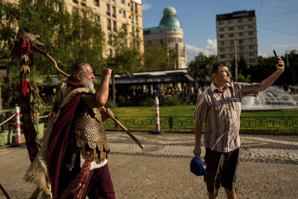 Constantin "The Castor" Lapusneanu, wearing a Dacian warrior outfit, clenches his fist as a man takes a selfie photograph in Iasi, Romania, Friday, July 11, 2025 ahead of the Getodava historical reenactment festival. (AP Photo/Andreea Alexandru)