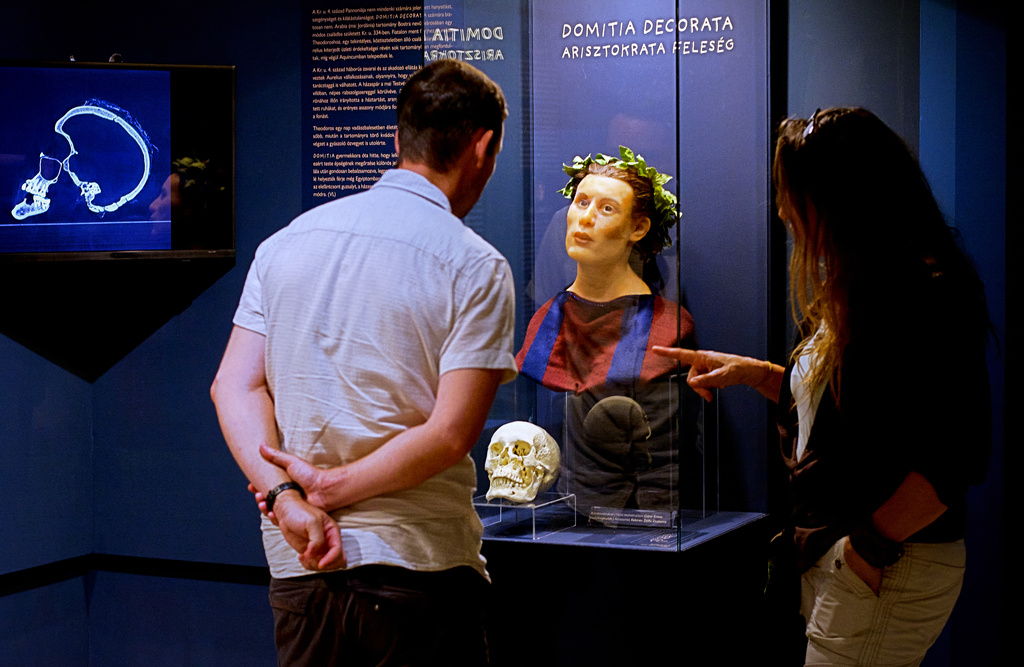 Visitors look at Roman-era skulls and their facial reconstructions in the Aquincum Museum's exhibition titled "Once we were like you" which showcases characters and the fictional life stories of those who once lived in the bustling Roman settlement of Aquincum, in Budapest, Hungary, Tuesday, July 7, 2026. (AP Photo/Bela Szandelszky)