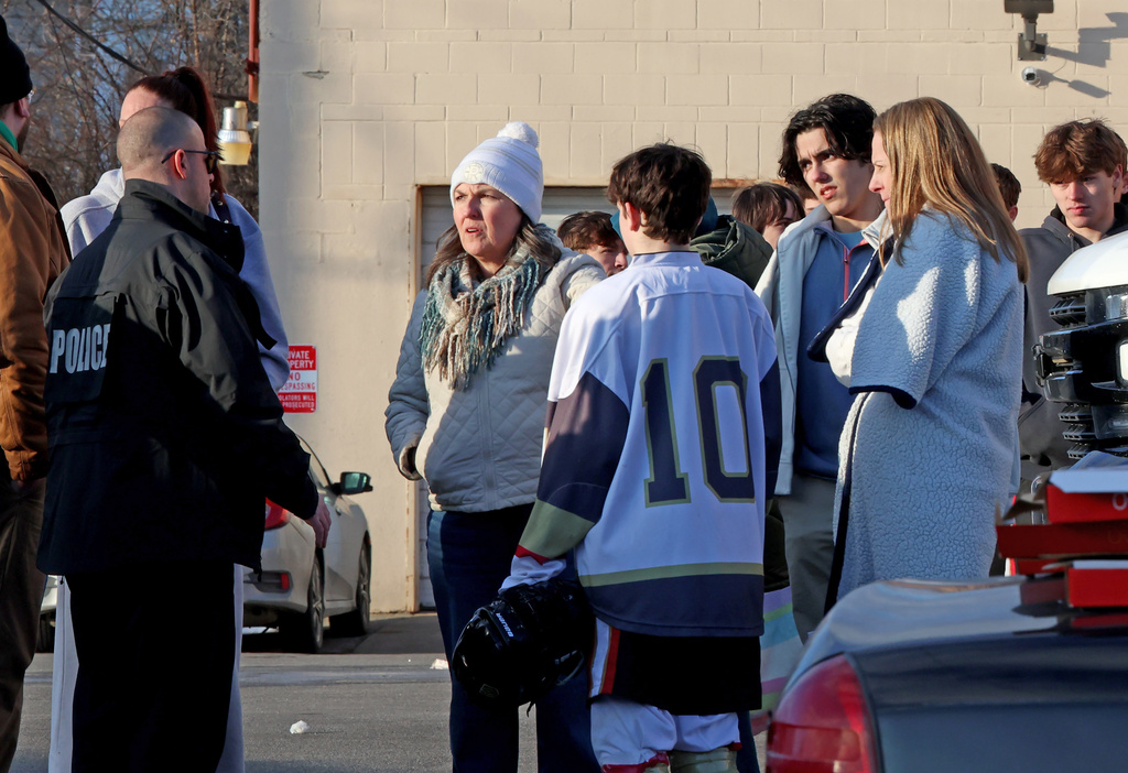 High school hockey players and parents speak to a police officer near the Lynch Arena in Pawtucket, R.I., after a shooting at the ice rink, Monday, Feb. 16, 2026. (AP Photo/Mark Stockwell)