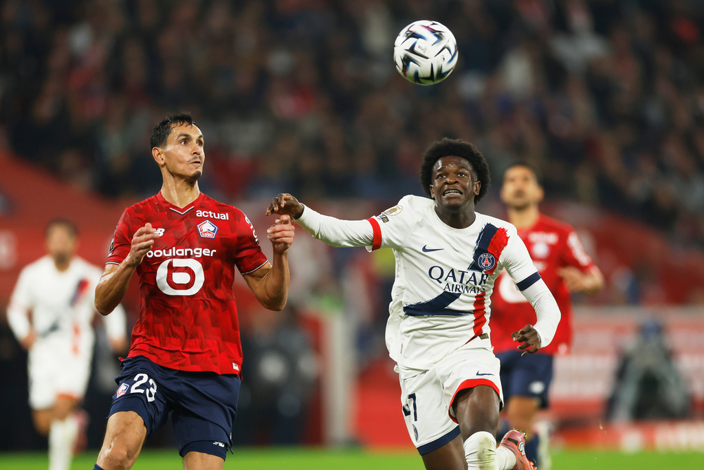 Lille's Aissa Mandi, left, and PSG's Quentin Ndjantou challenge for the ball during the French League One soccer match between Lille and Paris Saint-Germain at the Stade Pierre-Mauroy in Villeneuve-d'Ascq, outside Lille, France, Sunday, Oct. 5, 2025. (AP Photo/Jean-Francois Badias)